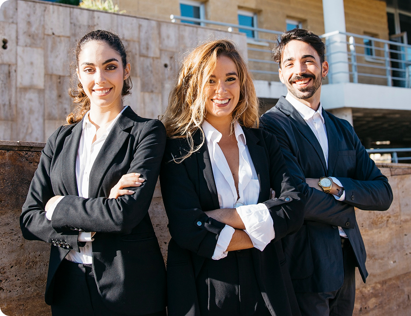 Tres profesionales del equipo comercial sonriendo con los brazos cruzados.
